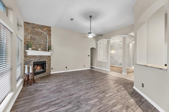 unfurnished living room with a fireplace, dark wood-type flooring, decorative columns, and ceiling fan