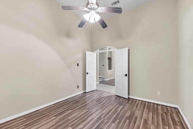 empty room with hardwood / wood-style floors, a towering ceiling, and ceiling fan