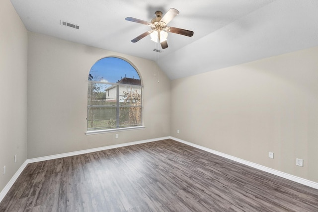 empty room featuring dark hardwood / wood-style flooring, vaulted ceiling, and ceiling fan