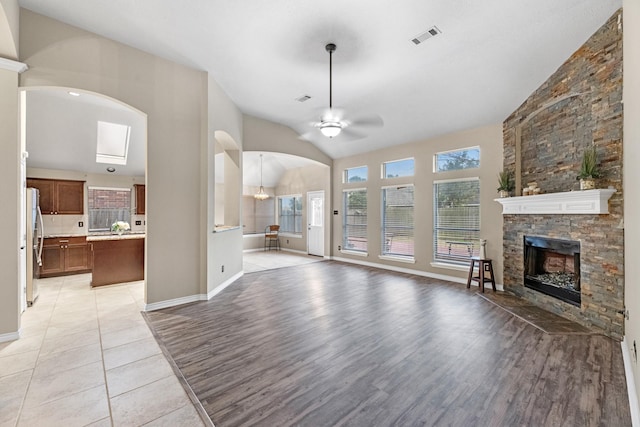 unfurnished living room featuring light hardwood / wood-style flooring, a fireplace, ceiling fan, and vaulted ceiling