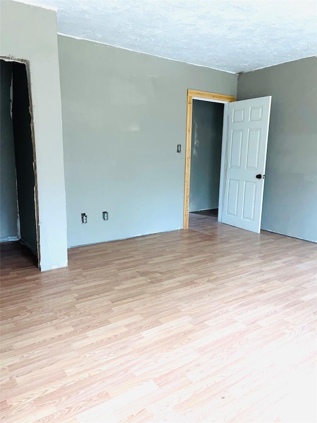 empty room featuring a textured ceiling and light hardwood / wood-style floors