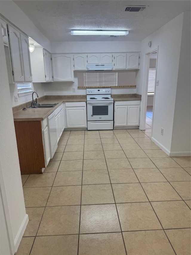 kitchen featuring sink, white cabinetry, a textured ceiling, light tile patterned floors, and white appliances