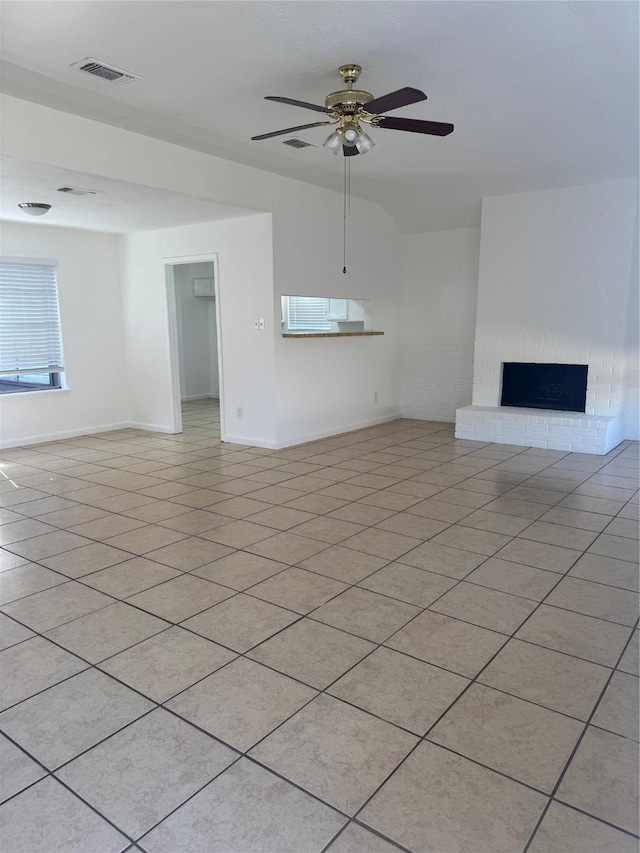 unfurnished living room with a brick fireplace, light tile patterned floors, and ceiling fan