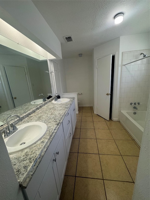 full bathroom featuring tiled shower / bath combo, vanity, toilet, tile patterned floors, and a textured ceiling