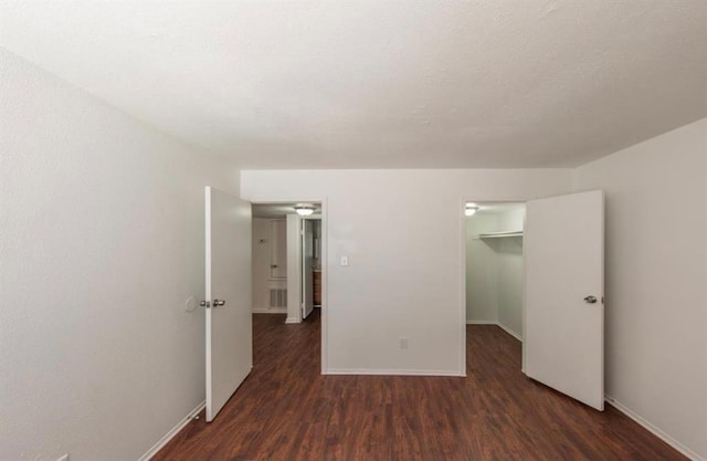 unfurnished bedroom featuring dark hardwood / wood-style flooring, a spacious closet, and a closet