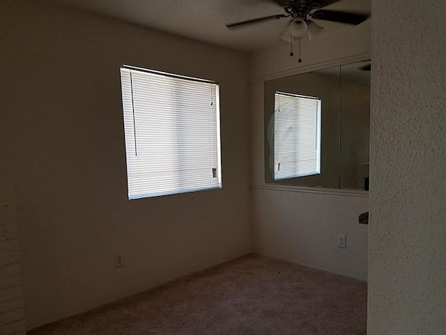 empty room featuring ceiling fan and light colored carpet