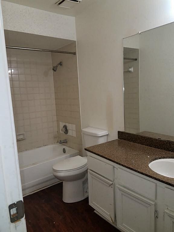 full bathroom featuring vanity, tiled shower / bath combo, wood-type flooring, and toilet