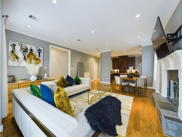 living room featuring crown molding, wood-type flooring, and a fireplace