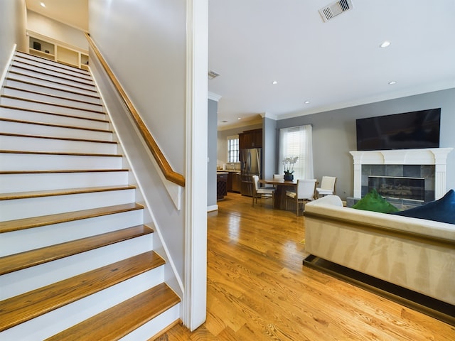 stairs featuring ornamental molding, hardwood / wood-style floors, and a fireplace