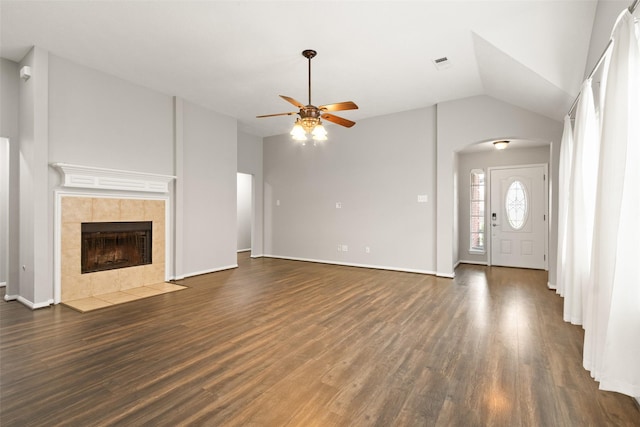 unfurnished living room with ceiling fan, dark hardwood / wood-style floors, a tiled fireplace, and vaulted ceiling