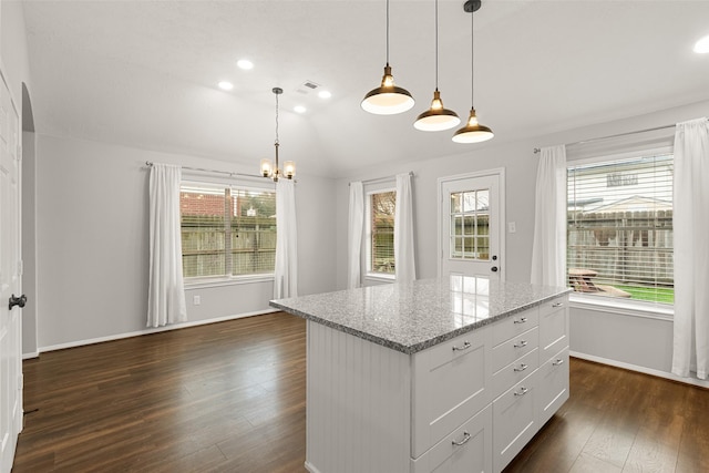 kitchen with lofted ceiling, white cabinets, hanging light fixtures, light stone countertops, and dark wood-type flooring