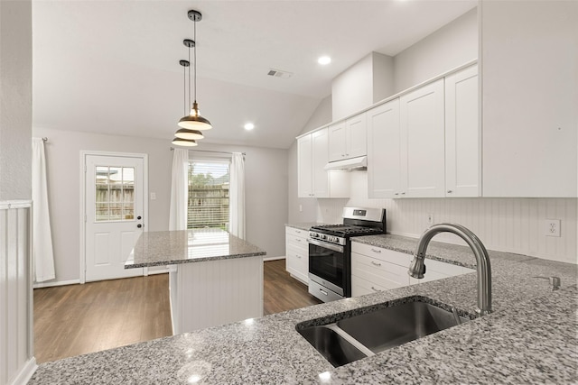 kitchen featuring sink, light stone countertops, gas stove, white cabinets, and decorative light fixtures