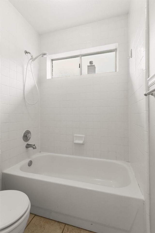 bathroom with toilet, tiled shower / bath combo, and tile patterned flooring