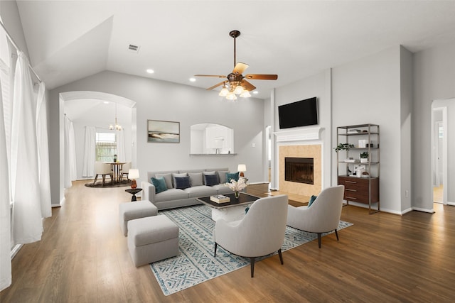 living room with dark wood-type flooring, vaulted ceiling, a tile fireplace, and ceiling fan