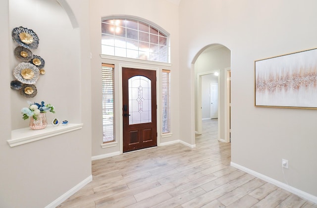 foyer entrance featuring light hardwood / wood-style flooring and a high ceiling