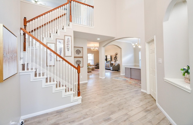 entrance foyer with an inviting chandelier, a towering ceiling, and light hardwood / wood-style floors