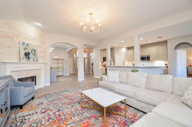 living room with an inviting chandelier, a fireplace, and light wood-type flooring