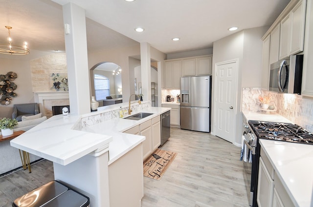 kitchen with appliances with stainless steel finishes, sink, backsplash, and an inviting chandelier