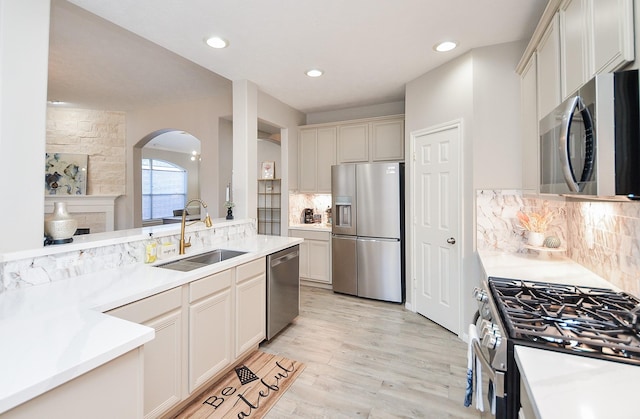 kitchen with stainless steel appliances, sink, light hardwood / wood-style floors, and decorative backsplash