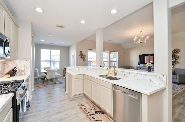 kitchen featuring sink, white cabinetry, backsplash, stainless steel appliances, and kitchen peninsula