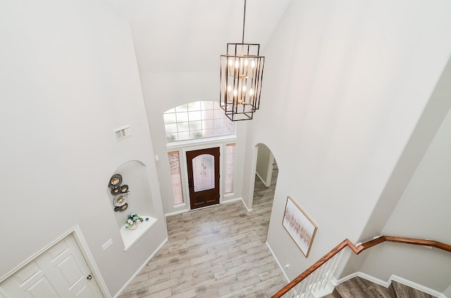 entrance foyer featuring a high ceiling, a notable chandelier, and light hardwood / wood-style flooring