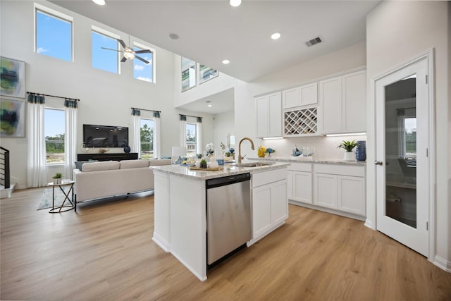 kitchen featuring stainless steel dishwasher, an island with sink, sink, and white cabinets