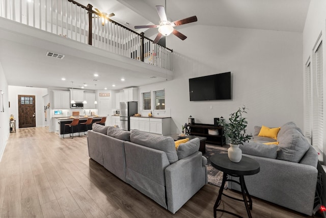 living room with a towering ceiling, hardwood / wood-style floors, and ceiling fan