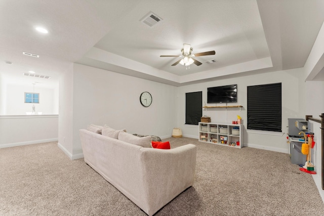 carpeted living room featuring a tray ceiling and ceiling fan