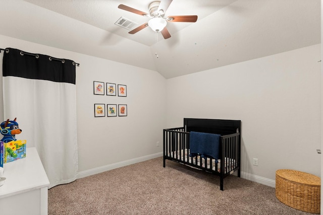 bedroom featuring a crib, vaulted ceiling, light colored carpet, and ceiling fan