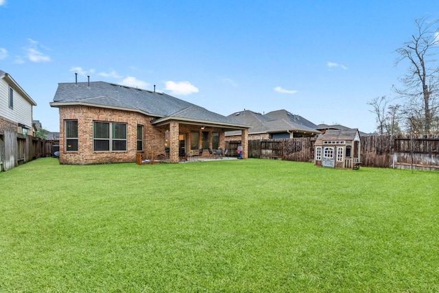 back of house with a yard, a patio area, and a shed