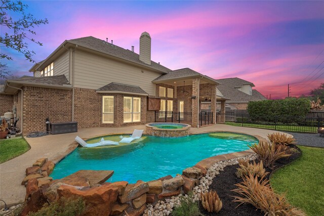 pool at dusk with a patio area and an in ground hot tub