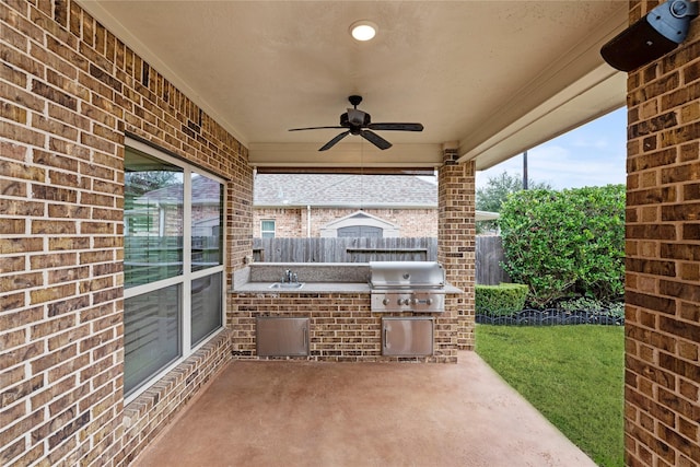 view of patio / terrace featuring a sink, a grill, a ceiling fan, fence, and exterior kitchen