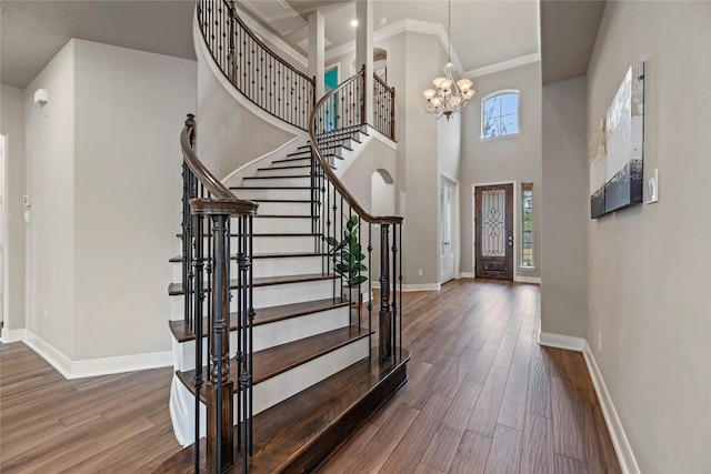 entryway featuring an inviting chandelier, a high ceiling, baseboards, and wood finished floors