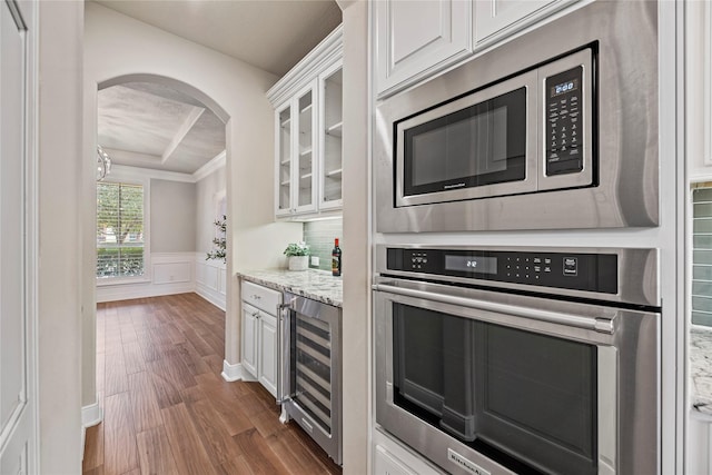 kitchen featuring wine cooler, stainless steel appliances, white cabinetry, a raised ceiling, and glass insert cabinets