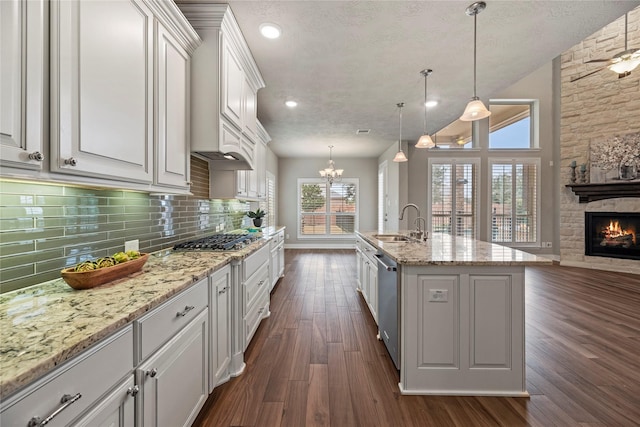 kitchen with open floor plan, white cabinets, hanging light fixtures, and an island with sink