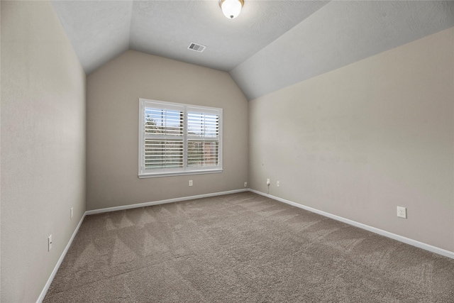 additional living space with a textured ceiling, visible vents, baseboards, vaulted ceiling, and carpet