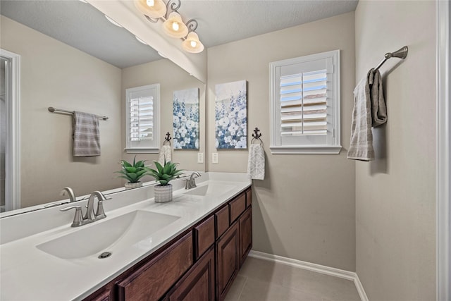 full bathroom featuring double vanity, baseboards, a sink, and tile patterned floors