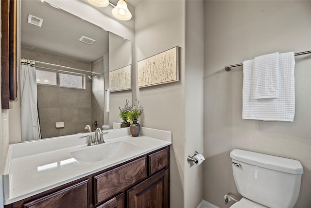 full bathroom featuring toilet, visible vents, a tile shower, and vanity