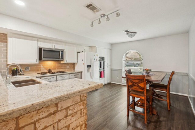 kitchen with sink, dark wood-type flooring, stainless steel appliances, light stone counters, and white cabinets