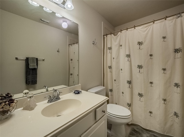 bathroom featuring toilet, vanity, and visible vents