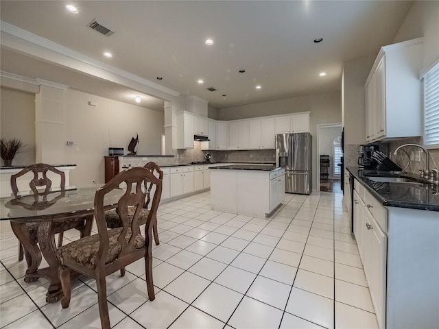 kitchen with a sink, white cabinets, stainless steel refrigerator with ice dispenser, a center island, and dark countertops