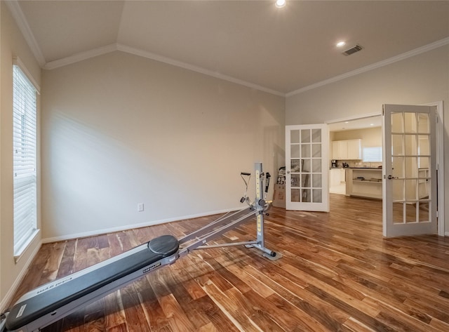 exercise area featuring wood finished floors, visible vents, vaulted ceiling, ornamental molding, and french doors