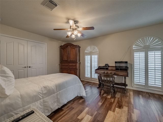 bedroom with ceiling fan, visible vents, baseboards, a closet, and dark wood finished floors