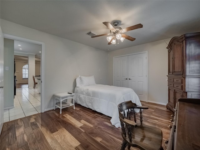 bedroom with baseboards, visible vents, a ceiling fan, light wood-style flooring, and a closet