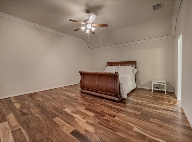 unfurnished bedroom with lofted ceiling, wood finished floors, visible vents, baseboards, and ornamental molding