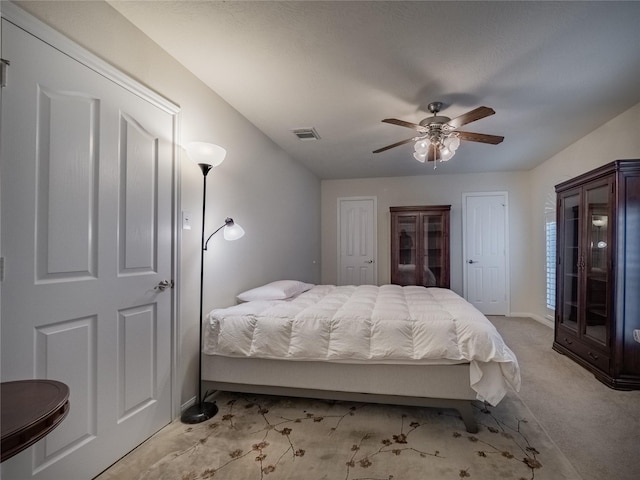 bedroom featuring baseboards, visible vents, light colored carpet, ceiling fan, and multiple closets