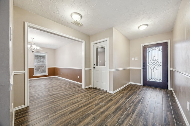 foyer entrance featuring dark wood-type flooring, a chandelier, and a healthy amount of sunlight