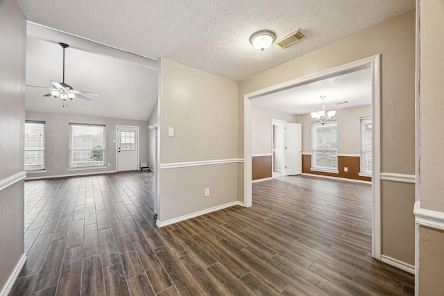 interior space with lofted ceiling, ceiling fan with notable chandelier, a textured ceiling, and dark hardwood / wood-style flooring