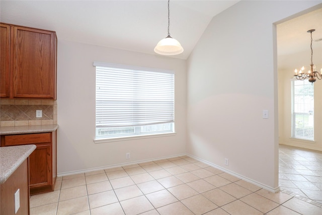 unfurnished dining area with vaulted ceiling, light tile patterned floors, and a chandelier