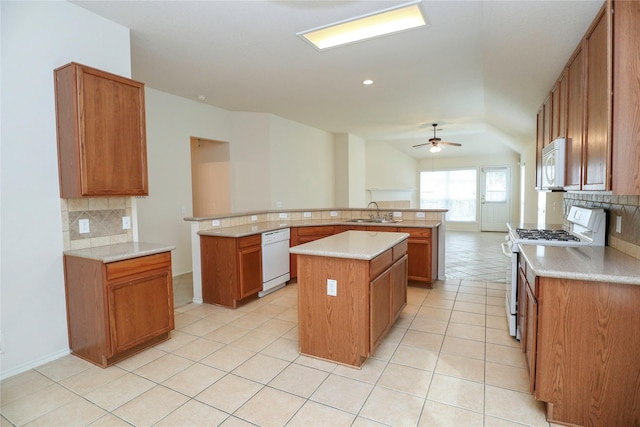 kitchen with tasteful backsplash, a center island, light tile patterned floors, kitchen peninsula, and white appliances